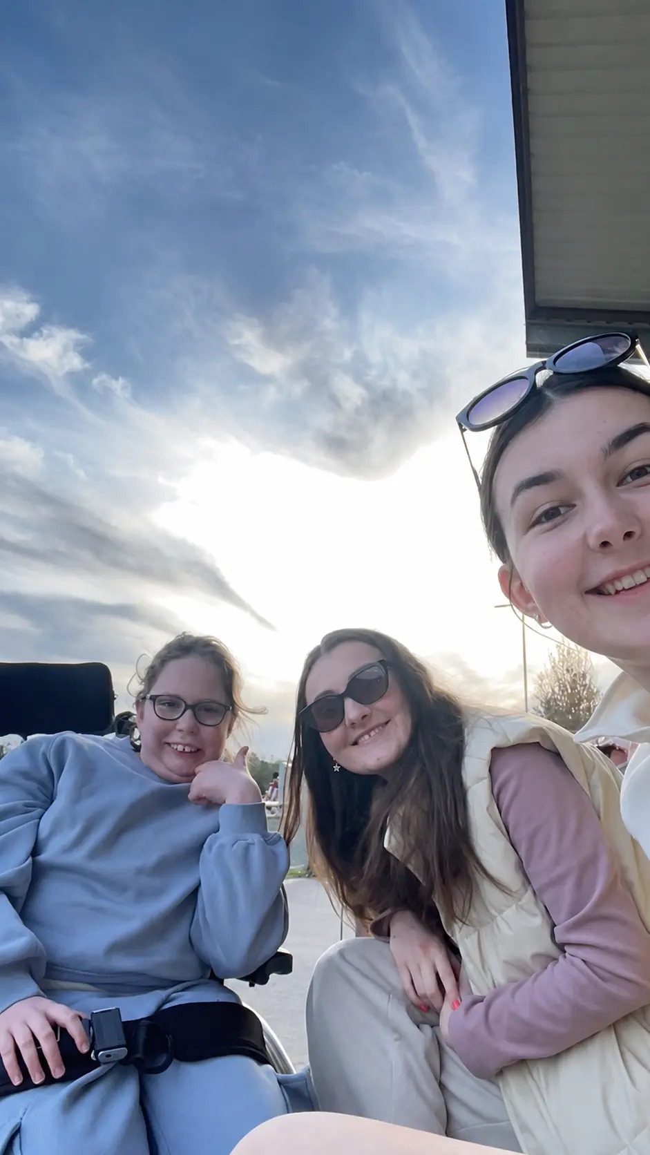 Three friends smiling together at sunset